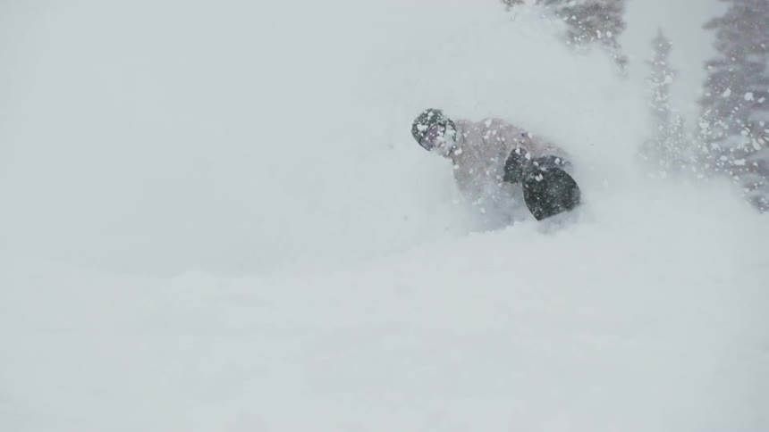 An extreme snowboarder rides through a massive cloud of fresh powder snow in super slow motion
