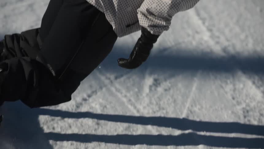 A dynamic, slow-motion close-up of a snowboarder carving down a snowy slope, kicking up a spray of powder