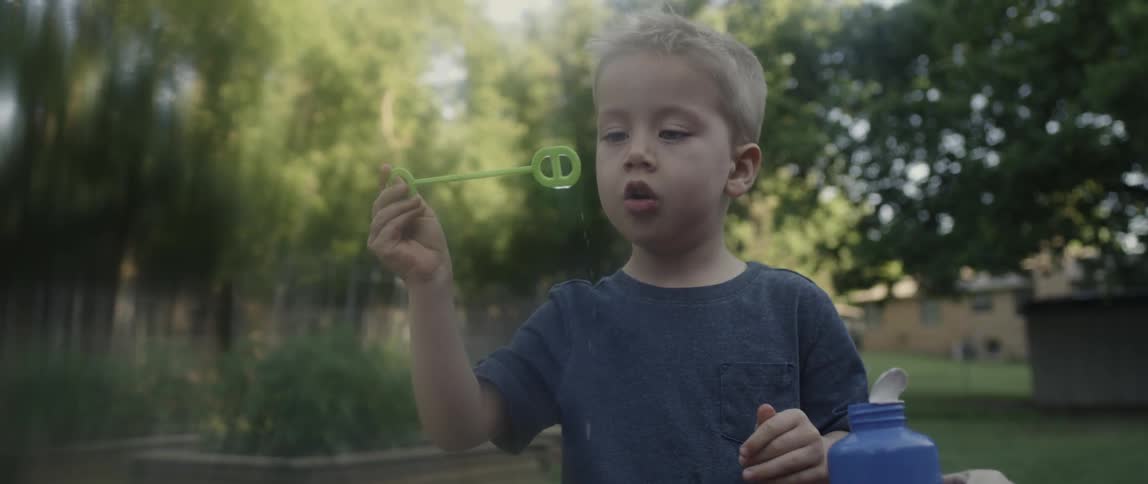 Child dips brush into container and blows bubbles