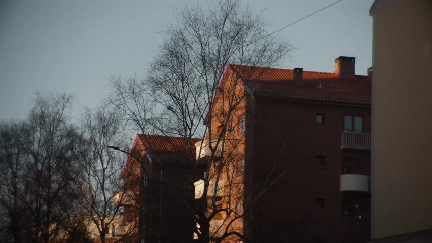 A European style brick apartment building is bathed in the warm glow of the setting sun