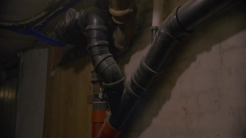 A slow pan across a dark and steamy basement reveals a complex network of old and new pipes