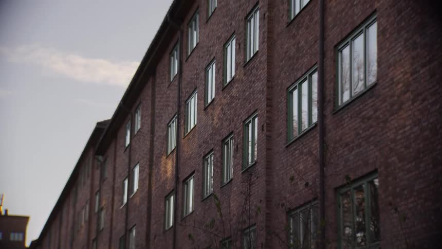 A static low-angle shot of a large red brick building's facade as the sun sets