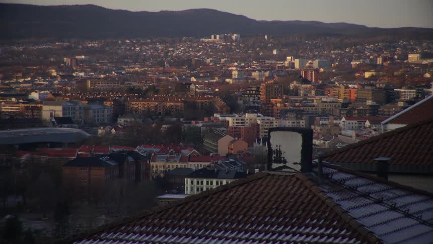 A high-angle view of a European cityscape with frosty rooftops in the foreground at sunrise