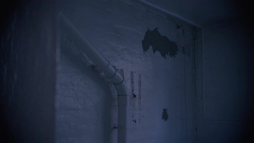 The ominous corner of a damp and decaying basement with peeling walls and exposed pipes