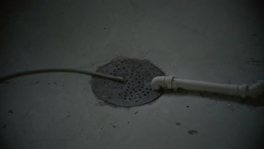 An eerie shot of a basement floor drain ends with a sudden, loud impact that knocks the camera over