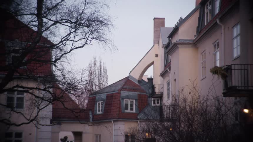 A still shot of a classic European apartment building with red roofs on an overcast day