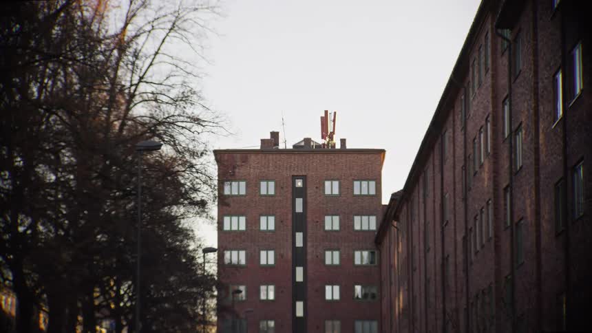 A cinematic slow zoom focuses on a classic red brick apartment building on a quiet city street as the sun sets