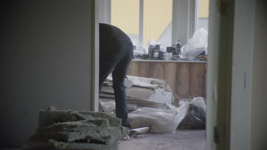 Two construction workers clean up debris in a room during a messy home renovation project