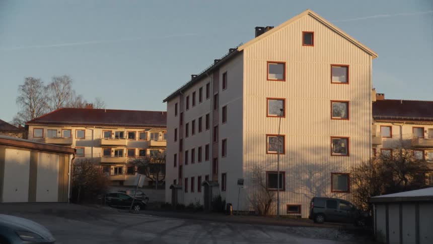 A slow zoom reveals a quiet residential neighborhood with apartment buildings bathed in the golden light of a cold morning sun