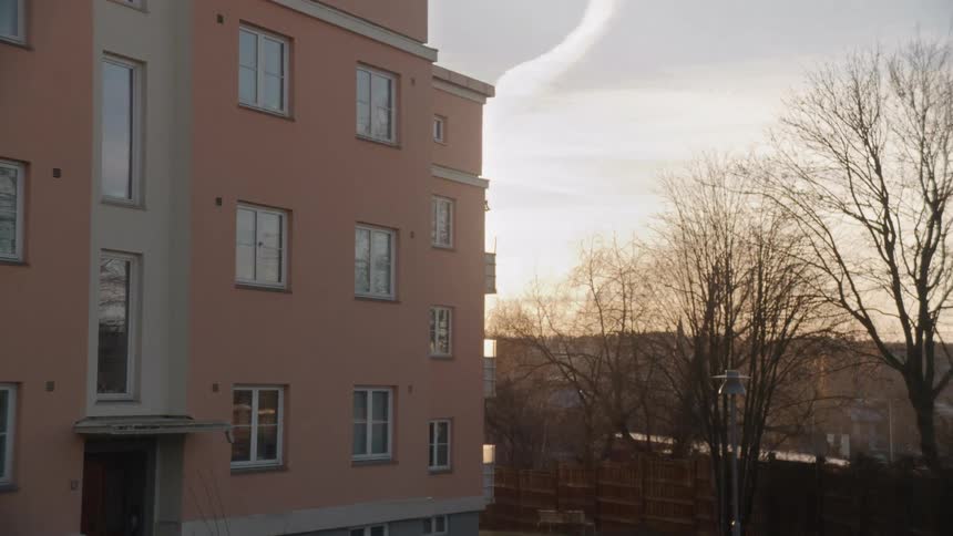 A slow zoom on a pink apartment building in a residential neighborhood during a golden hour sunset