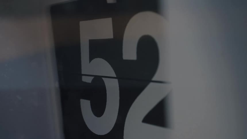 A close-up shot of the numbers on a black and white flip clock counting up every second