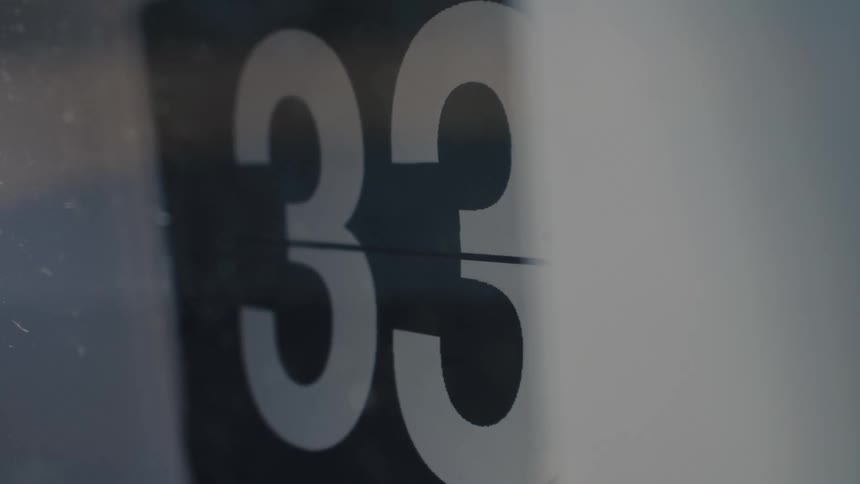 A close-up of a vintage flip clock as the number changes from thirty-two to thirty-three