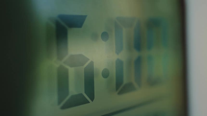 Close-up of a flashing digital alarm clock showing 6:00 AM, signaling the start of a new day