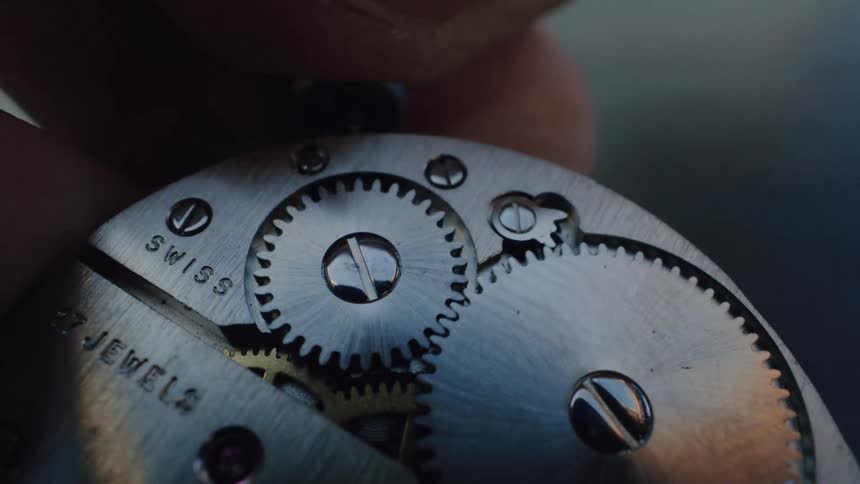 A detailed macro shot captures the intricate turning gears inside a vintage Swiss watch movement