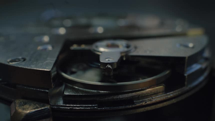 A macro detail shot shows the rhythmic oscillation of a balance wheel inside an old mechanical timepiece