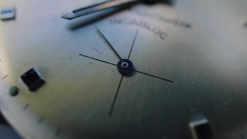 The second hand of a minimalist analog watch ticks steadily in a detailed macro view