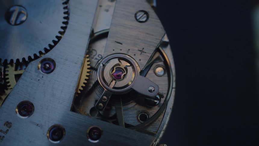 A detailed macro shot captures the intricate inner workings of a classic mechanical watch in continuous motion
