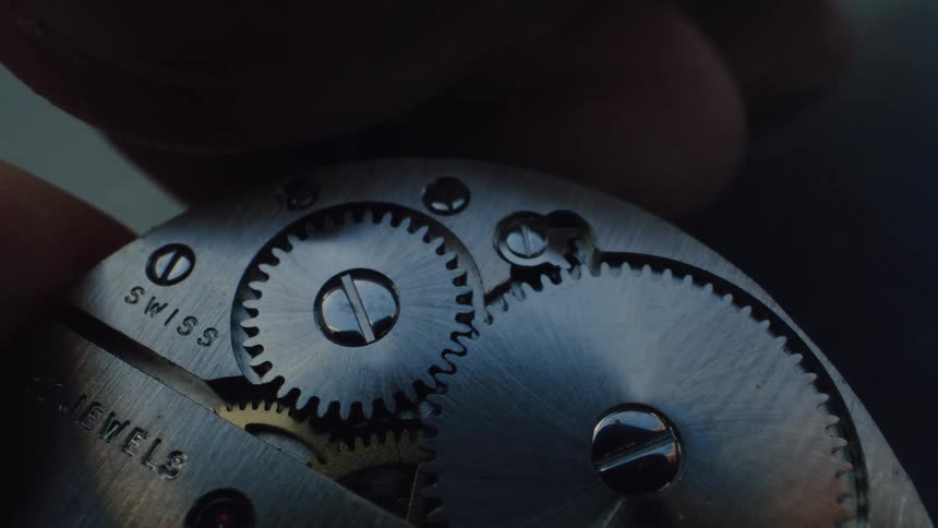 Macro shot of the intricate metal gears turning inside a classic Swiss timepiece
