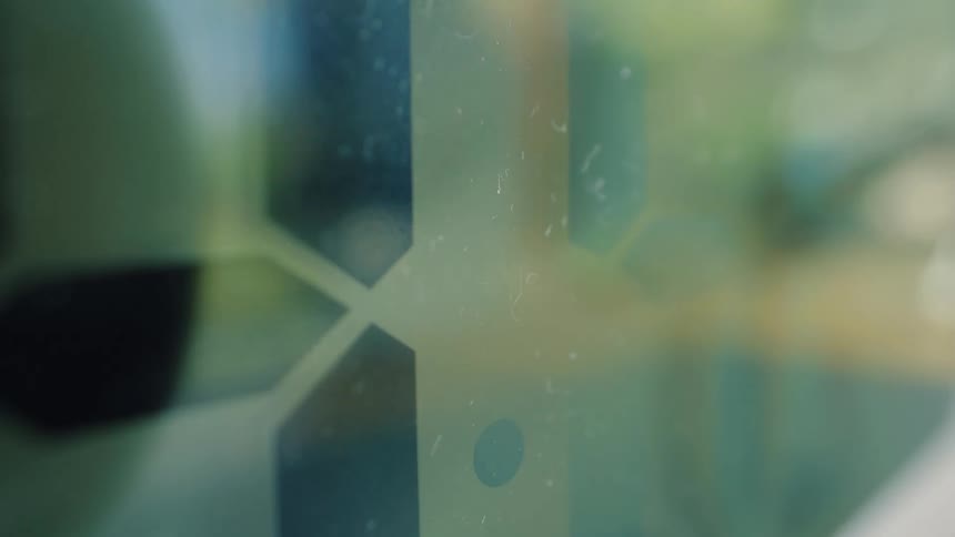 A dark droplet of liquid moves slowly through the channels of a microfluidic chip in a science laboratory