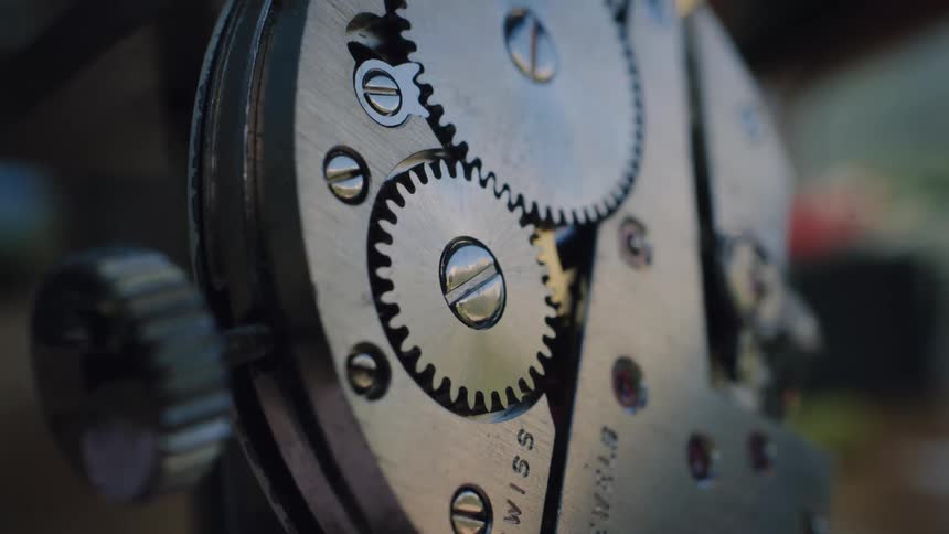 Detailed macro footage of a clock's internal gears working in unison