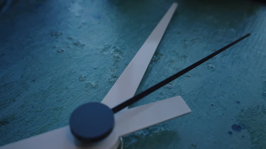 Close-up of a second hand smoothly sweeping across a moody, textured blue clock face