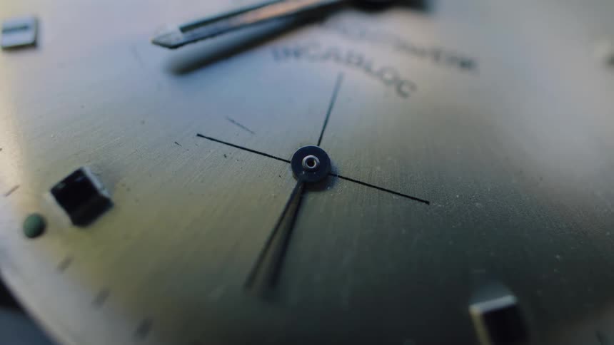 Extreme close-up of an old, dusty analog watch face with the second hand steadily ticking, marking the passage of time