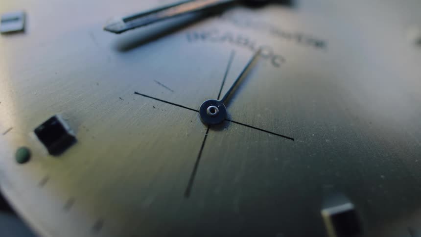 An extreme close-up of the second hand ticking on an old analog watch face, marking the steady passage of time