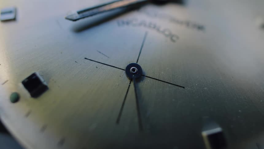 Seconds tick by on the face of an analog watch in an extreme macro shot