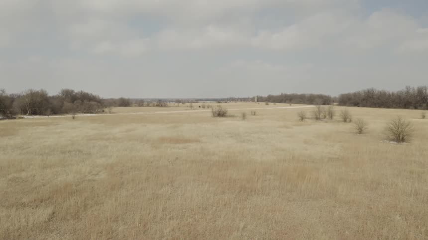Slowly pushing forward over a vast field of dry, dormant grass on a cold, overcast day