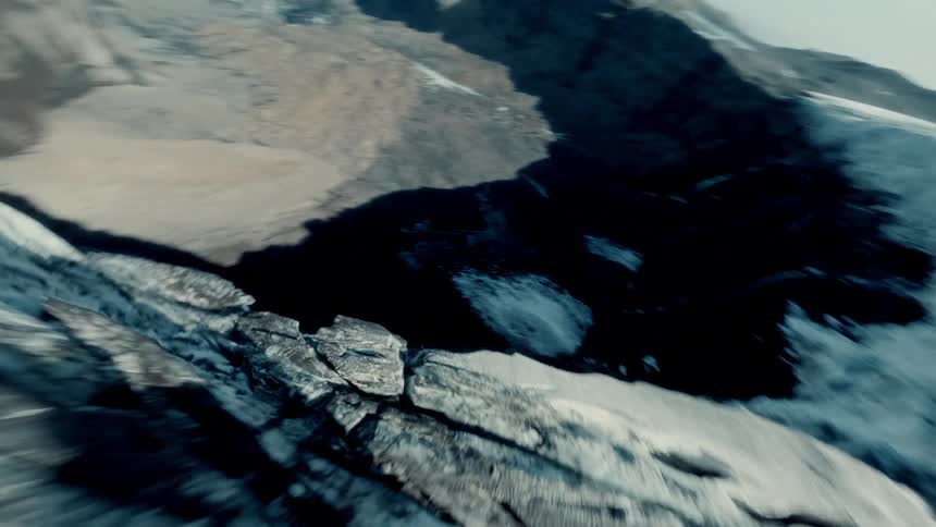 An exhilarating FPV drone flight soars along the jagged edge of a massive arctic glacier, revealing stunning waterfalls cascading down the sheer rock face