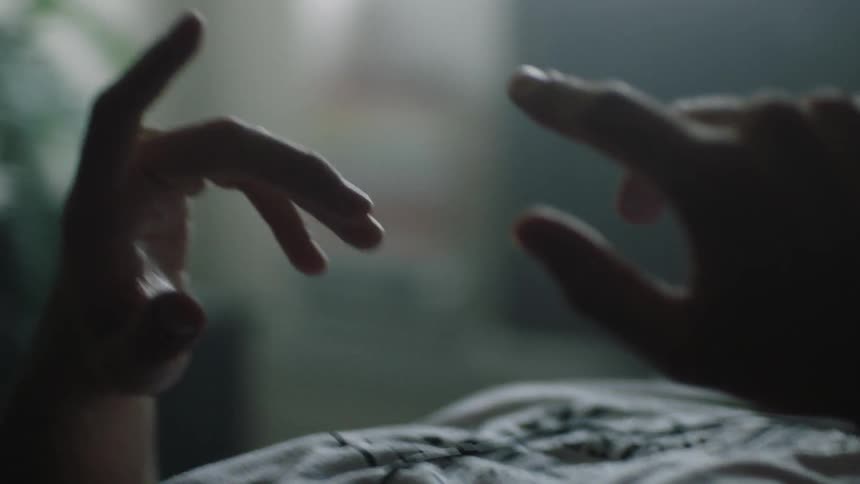 A man lays in bed moving his fingers around