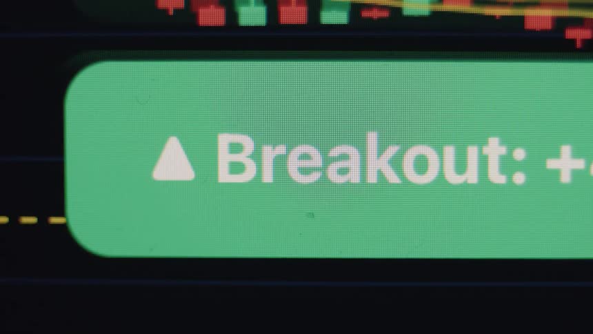 A macro close-up of a green 'Breakout' notification with an upward arrow appearing on a digital stock market or cryptocurrency trading chart