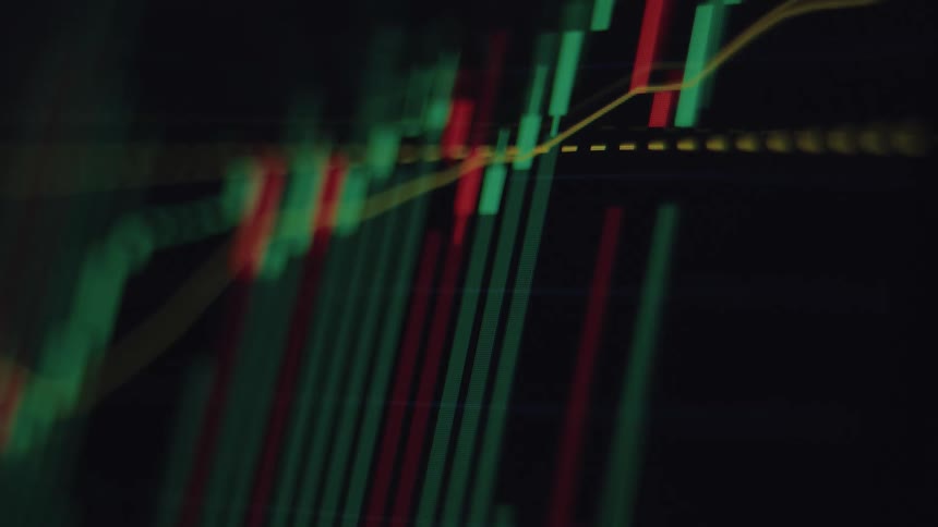 An out-of-focus close-up of a live stock market or cryptocurrency candlestick chart showing real-time price fluctuations