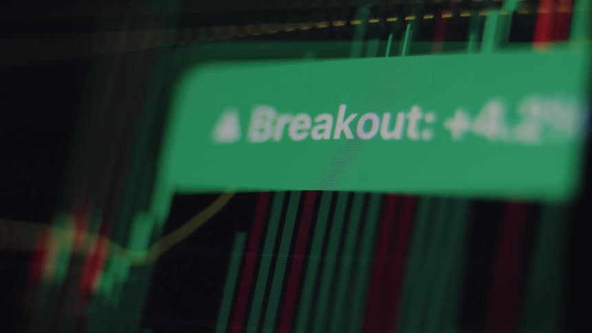 A digital stock market chart shows a bullish breakout with a green notification indicating a significant price increase