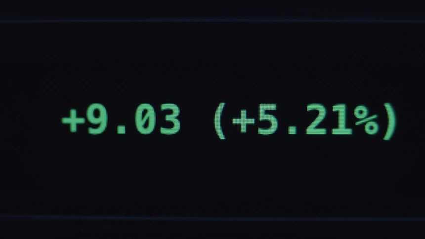 Close-up of a digital stock market ticker shows positive growth with green numbers fluctuating on a dark screen