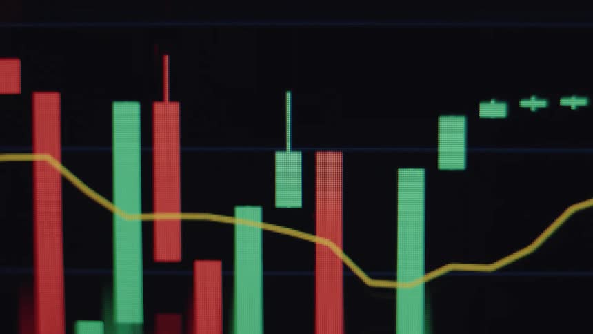 A close-up macro view of a financial candlestick chart with red and green bars fluctuating on a digital screen