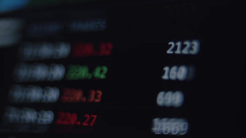 A blurry, out-of-focus close-up of a digital stock market ticker with fluctuating numbers on a dark screen