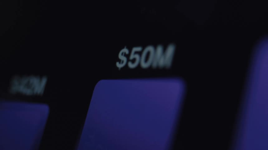 A close-up macro shot of a digital display shows financial figures rapidly increasing into the millions of dollars