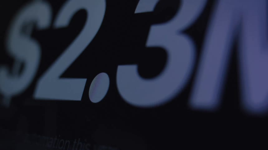 A close-up macro shot of a digital counter on a screen rapidly increasing to over two million dollars