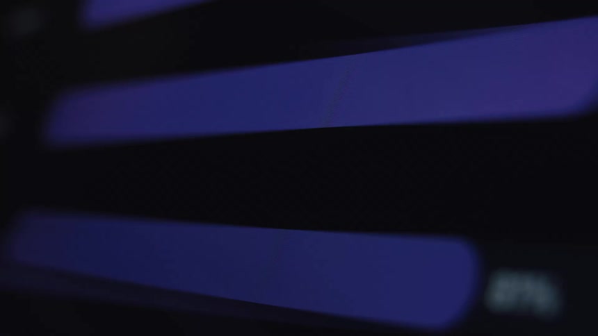 An angled macro shot shows purple progress bars with increasing percentages loading on a dark computer screen