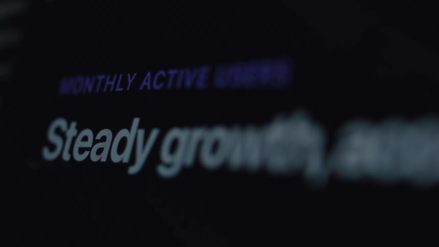 A macro close-up of a computer screen displays business metrics showing 'Steady growth' for monthly active users