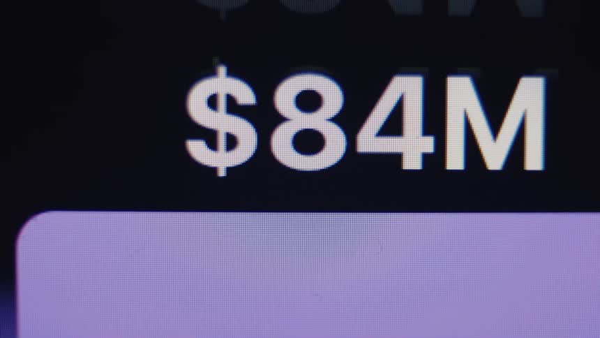 A close-up of a digital counter rapidly increasing to over 84 million dollars on a screen