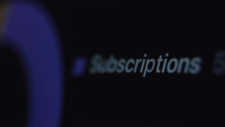 A close-up macro shot of the word 'Subscriptions' on a computer screen in a dark room
