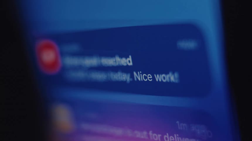 A close-up shot of a smartphone screen receiving a notification for reaching a 10,000 step health goal