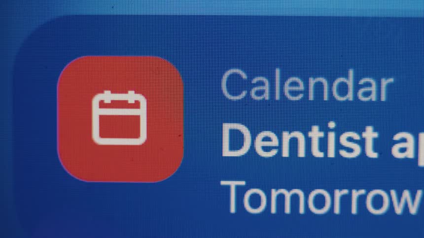 A macro close-up of a digital screen displays a calendar notification for a dentist appointment scheduled for tomorrow