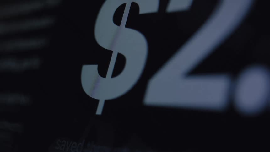 A close up of a digital counter with a dollar sign rapidly increasing in value on a dark computer screen