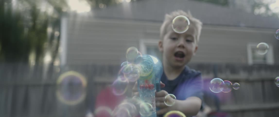A kid plays with a bubble gun