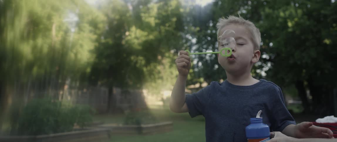 A boy is blowing bubbles in the yard