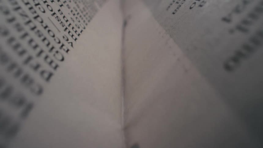 An extreme close-up macro shot slowly travels along the center crease of an open book, revealing the text