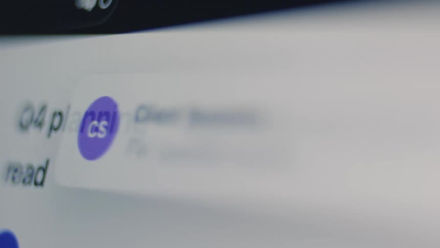 A person quickly scrolls through their business email inbox, revealing various subjects and senders on a bright computer screen